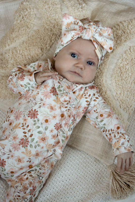 Pfirsichfarbener Strampler mit Rüschen und Blumen