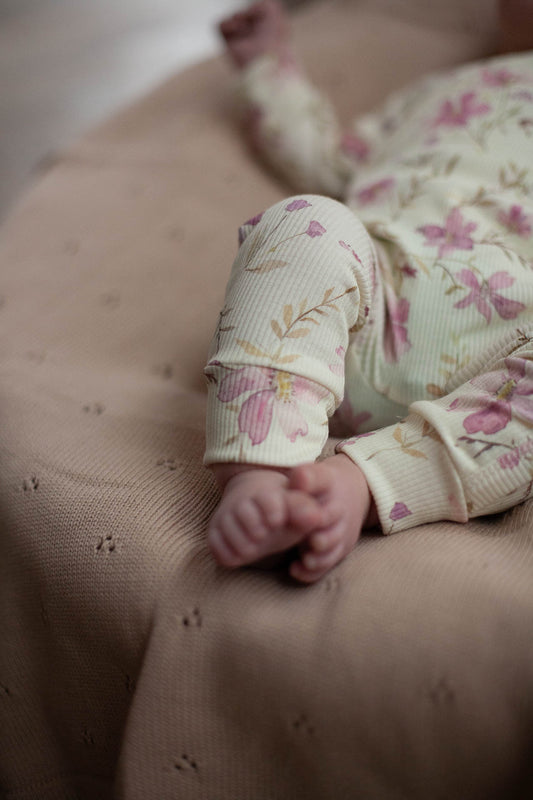Babystrampler im Rippenmuster, pastellgelb mit lila Blumen